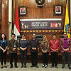 Image of 11 people standing in front of a banner and some flags at the Rabies vaccine handover event in Bali