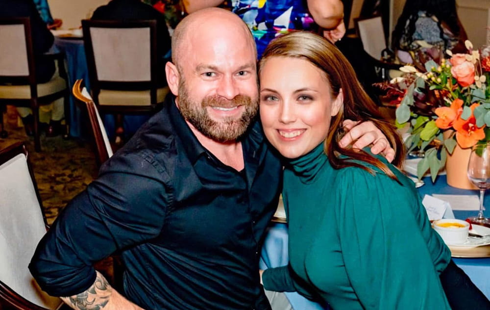 a couple poses together at a table at a fancy dinner