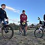 Three men sit on their BMX bikes in an open field