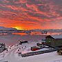 A large building in the snow and a setting sun in the sky above