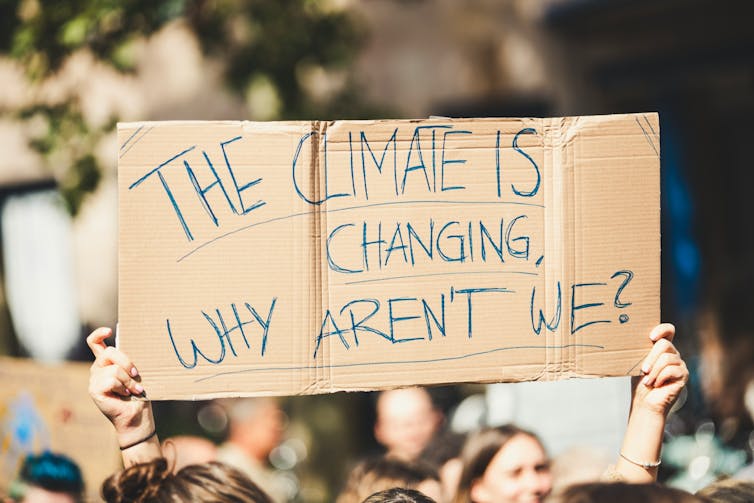 A person holds a sign that reads