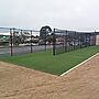 New black wire-mesh fencing around fresh artificial turf surrounded by freshly seeded earth with Bombala street scene in background