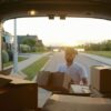 A man unloads moving boxes from the back of a van.