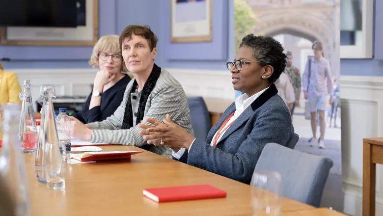 Women leaders, Tania Rhodes-Taylor, Professor Rachel A. Mills, and Professor Funmi Olonisakin, gathered around a conference table.